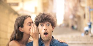 Beautiful young woman whispering a secret into her boyfriend's ear