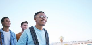A man and friends walking to class on university or college campus as exchange students. Study, scholarship and learning with a male friend group in a city or town